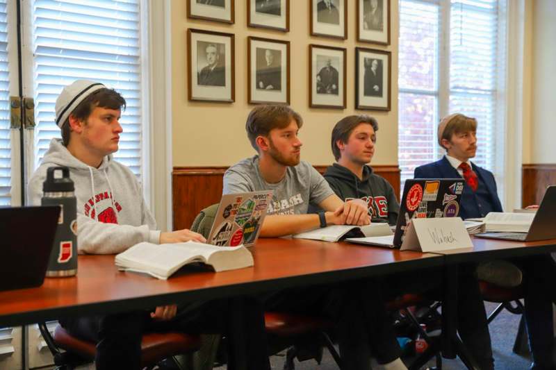 a group of men sitting at a table with laptops