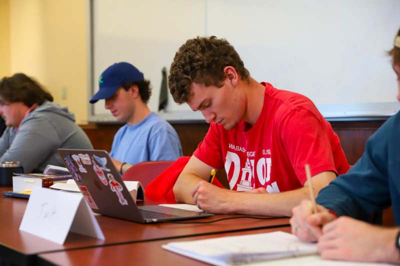 a group of people sitting at a table with laptops