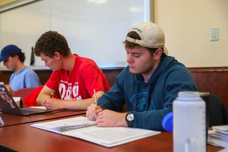 a group of people sitting at a table writing on papers