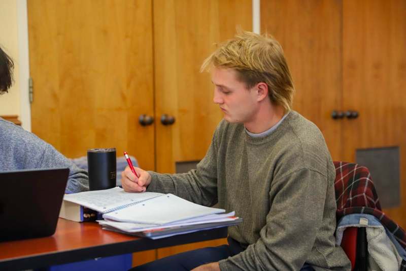 a man sitting at a table writing on a book