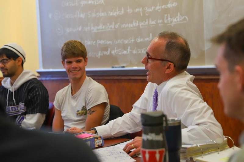 a man in white shirt talking to a young man