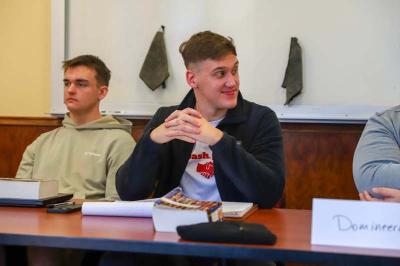 a man sitting at a table with his hands folded