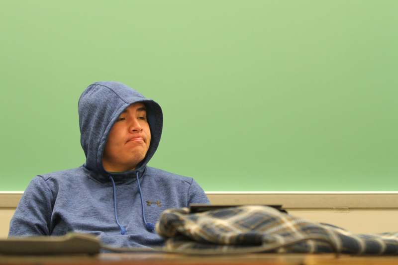 a man in a hoodie sitting at a desk