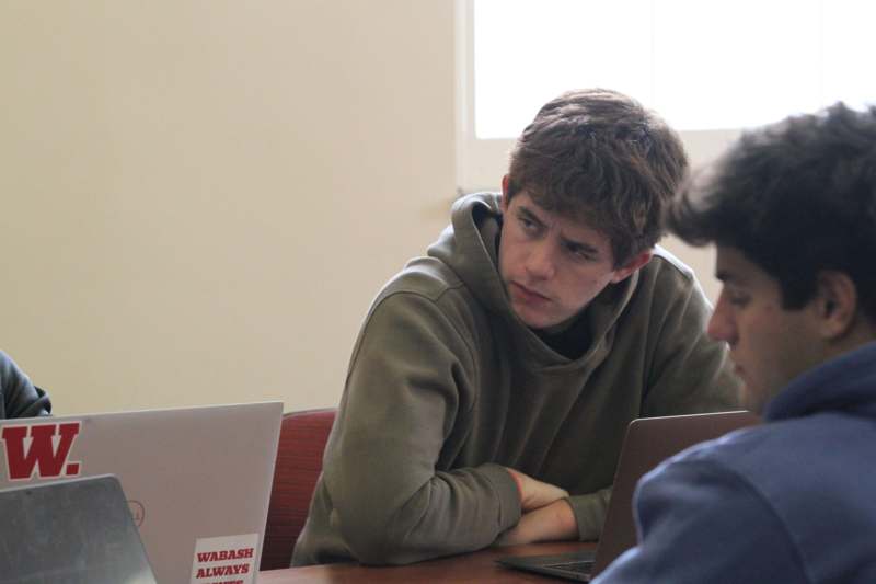 a group of people sitting at a table looking at a laptop
