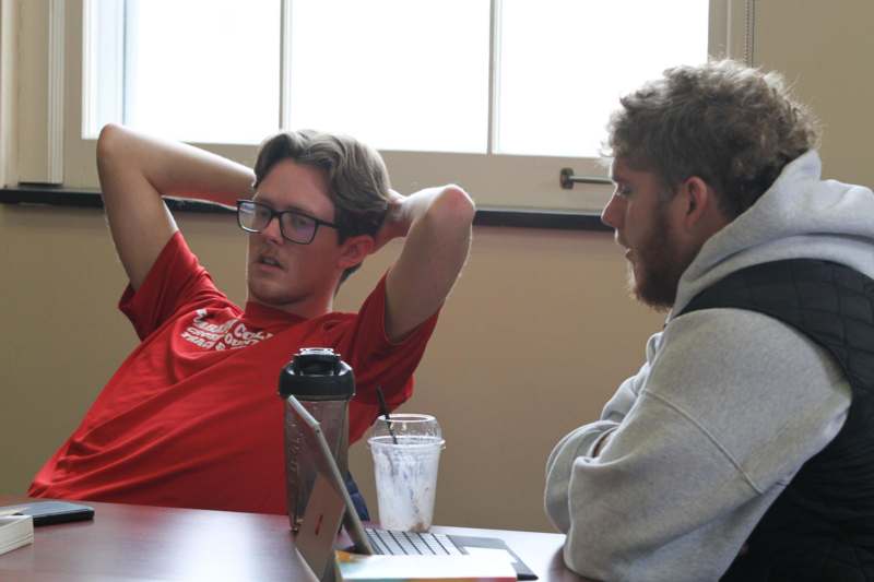 two men sitting at a table with their hands behind their head