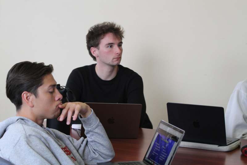 a group of men sitting at a table with laptops