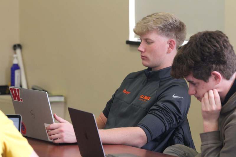 a group of men sitting at a table looking at a laptop