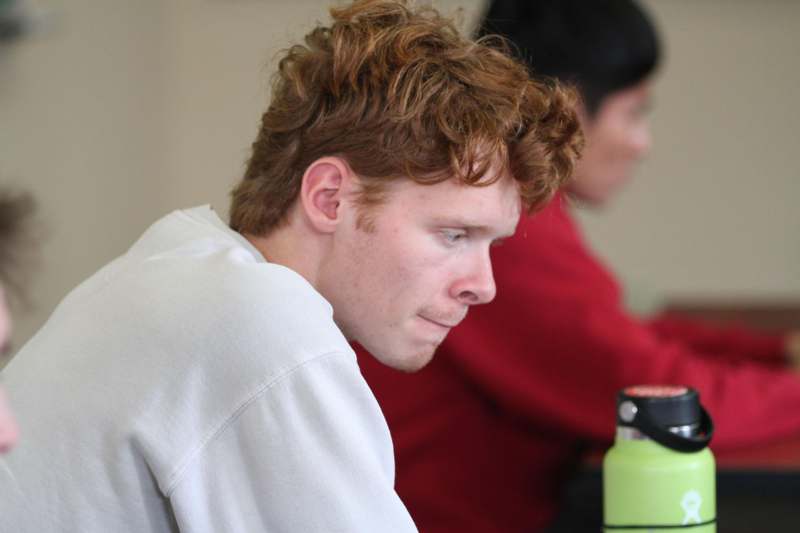 a man looking down at a green bottle