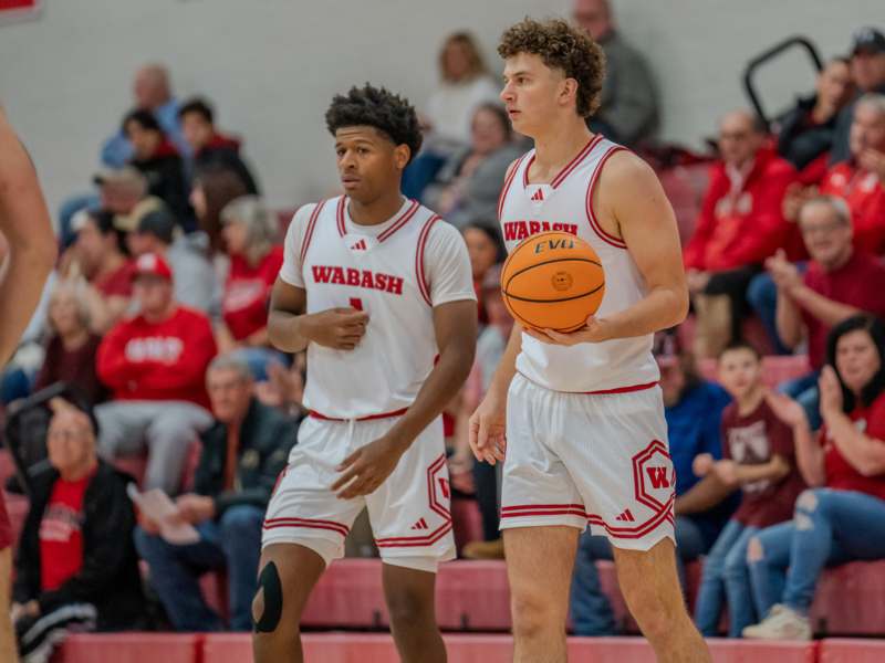 two men in sports uniforms holding a basketball