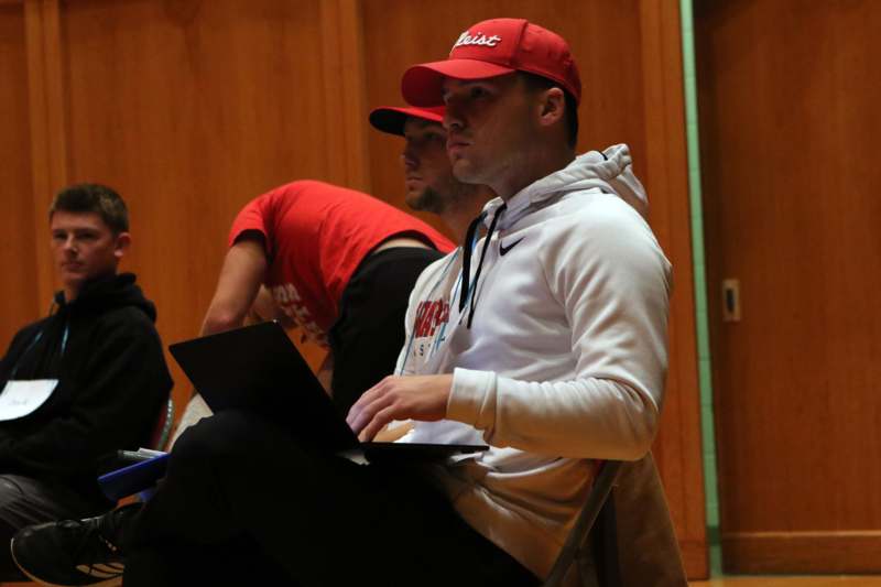 a man in a red hat sitting in a chair with a laptop