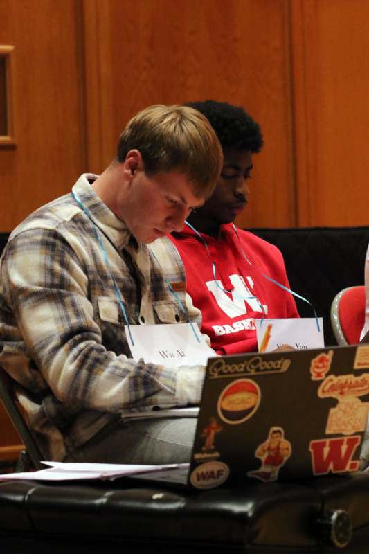 a group of men sitting in a chair looking at a laptop