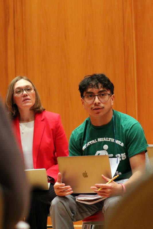 a man and woman sitting in front of a wood wall