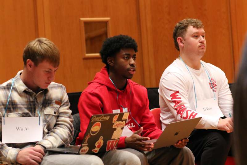 a group of men sitting in chairs with laptops