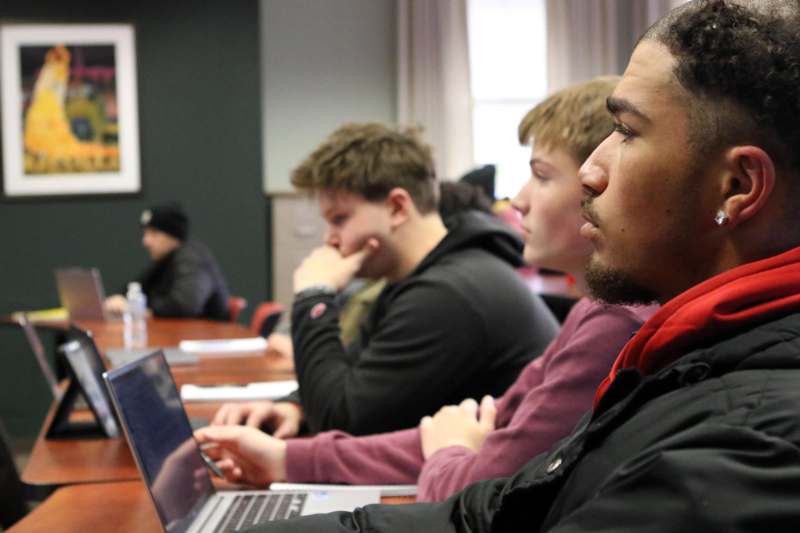 a group of people sitting at a table with laptops