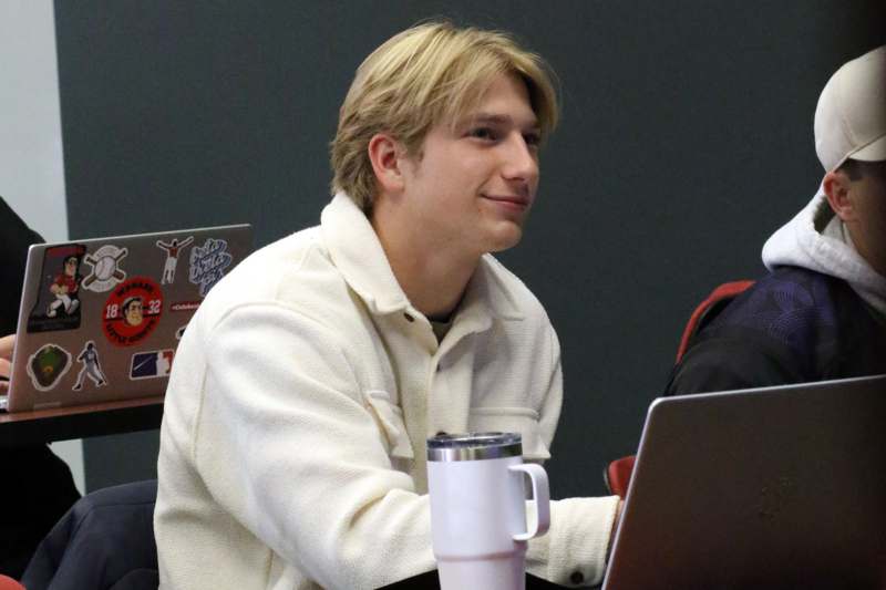 a man sitting at a table with a laptop and a mug