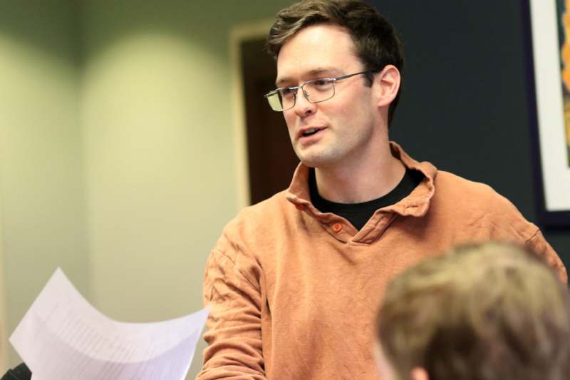 a man in glasses holding a piece of paper