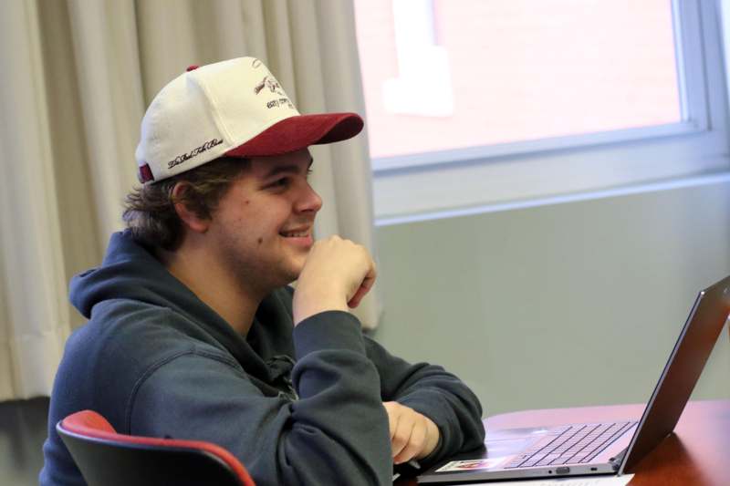 a man in a hat looking at a laptop