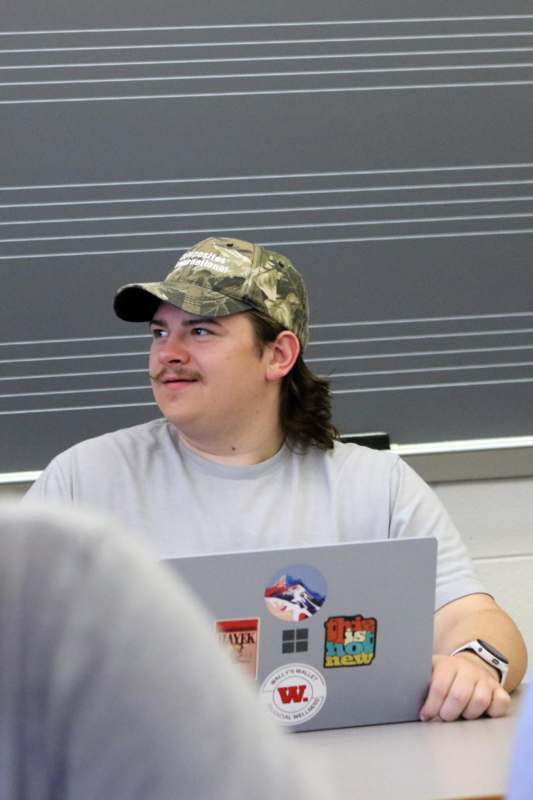 a man wearing a hat and holding a laptop