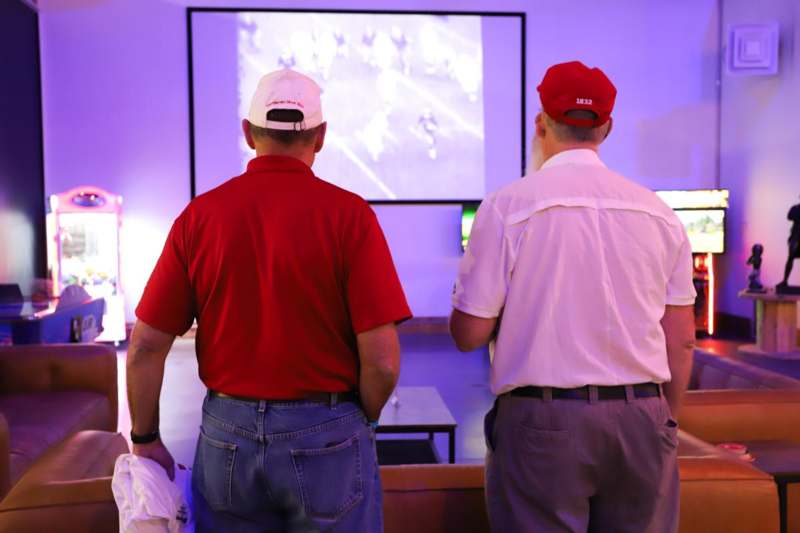 two men in red shirts and hats looking at a screen
