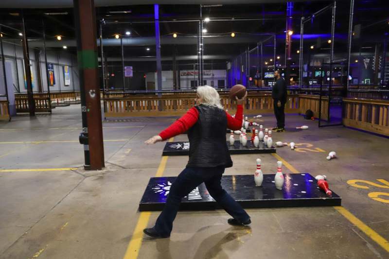 a woman throwing a football in a bowling alley
