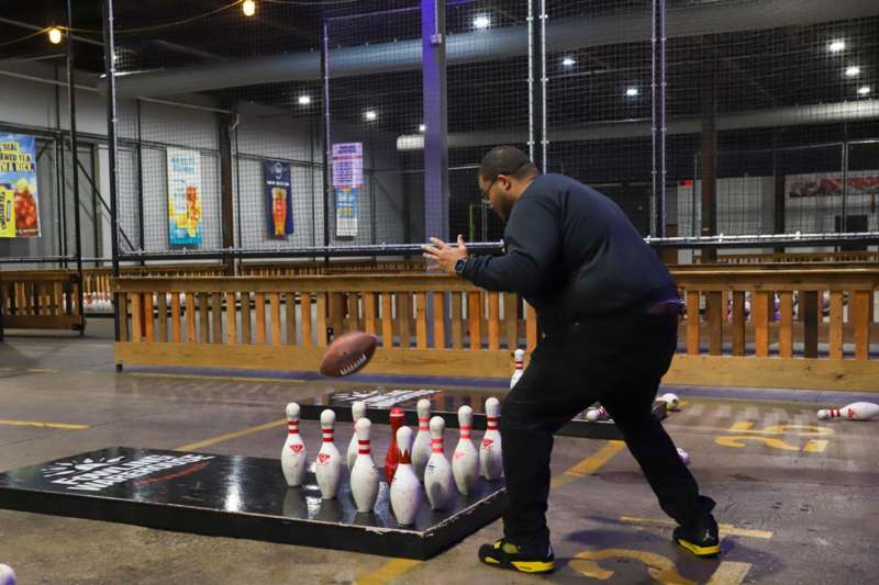 a man throwing a football in a bowling alley