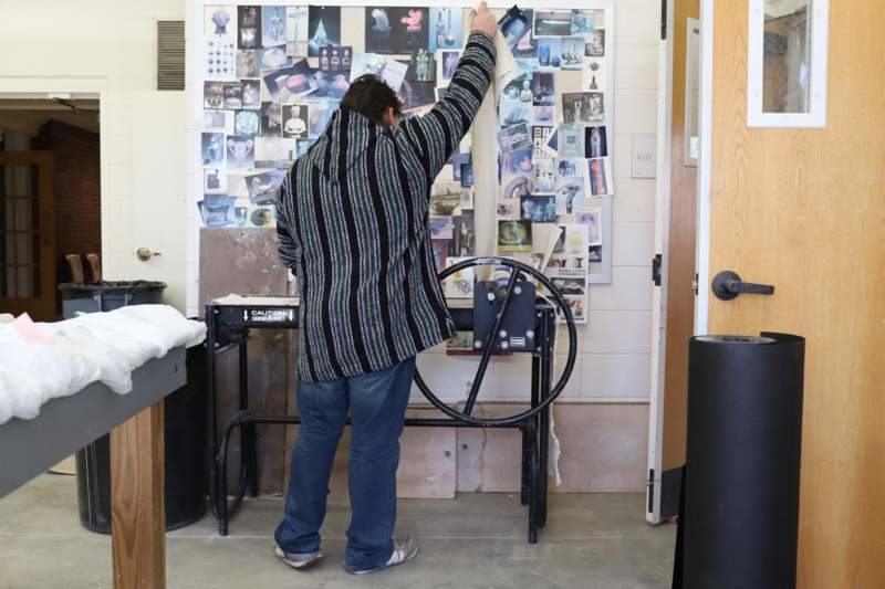 a man looking at a wall with pictures on it