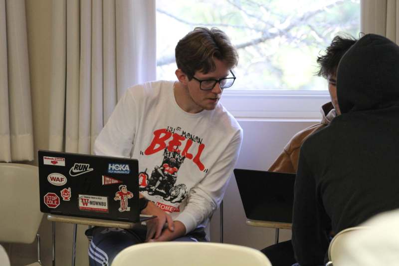 a group of people sitting in a room with laptops