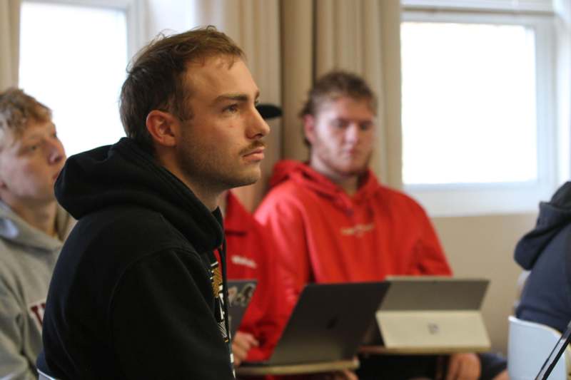 a group of men sitting in front of laptops