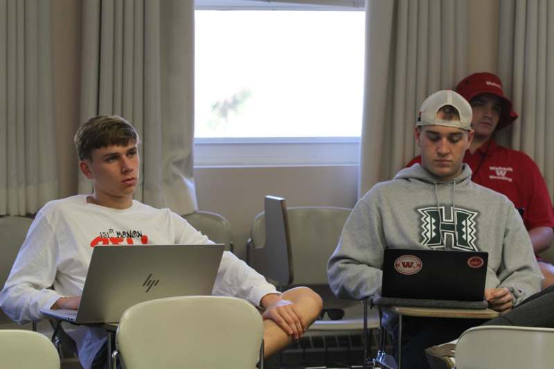 a group of men sitting at desks with laptops