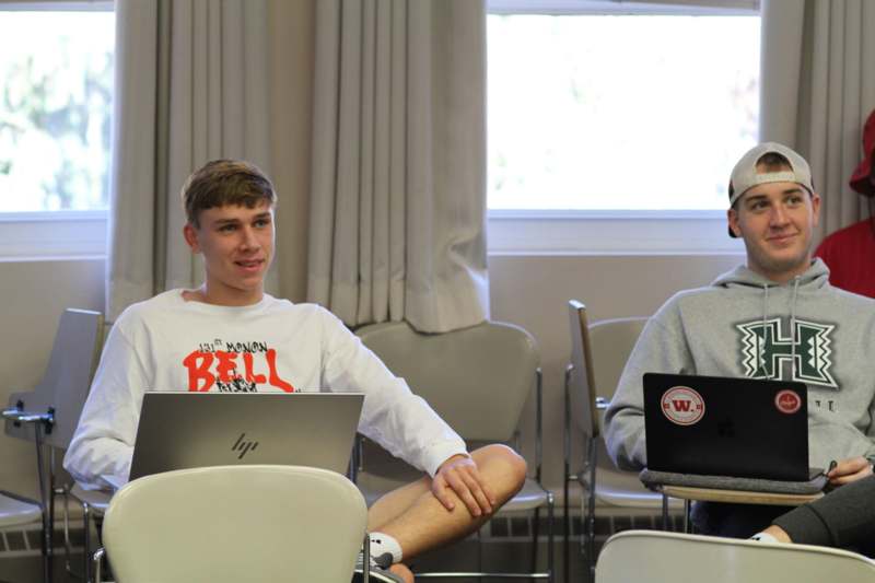 a group of people sitting at tables with laptops