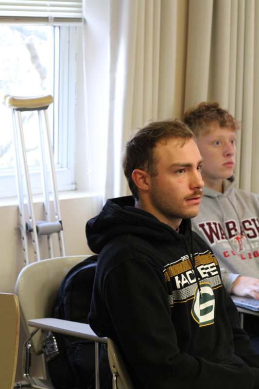 a man sitting in a chair with a man in a sweatshirt