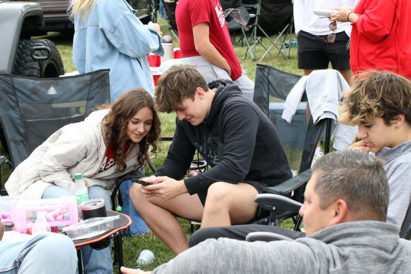 a man and woman sitting in chairs and looking at a phone