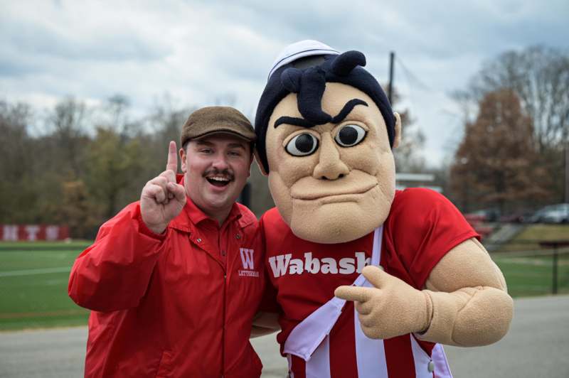a man standing next to a mascot