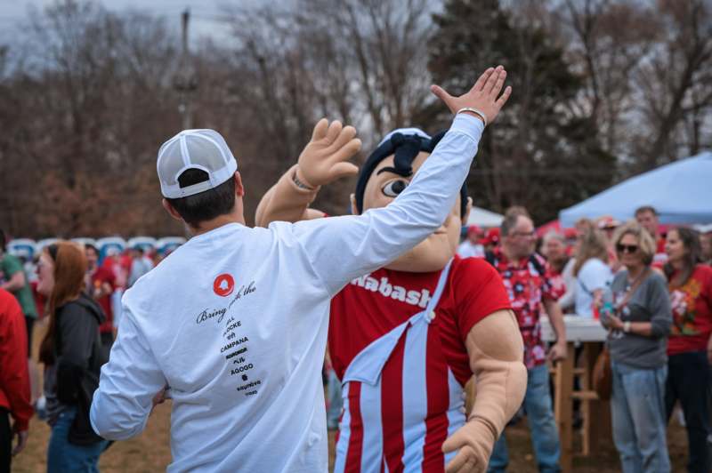 a man in a white hat reaching out to a person in a garment