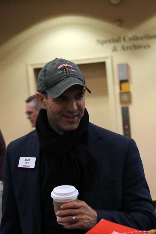 a man wearing a hat and a jacket holding a coffee cup