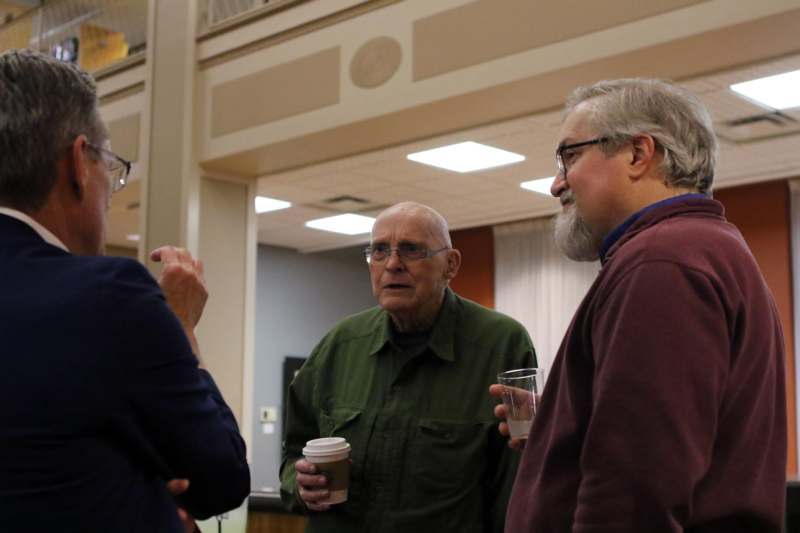 a group of men talking and drinking coffee