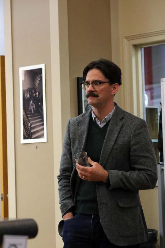 a man with a mustache holding a glass