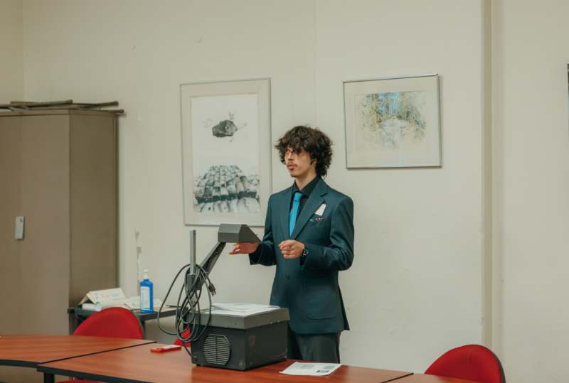 a man in a suit standing in front of a desk