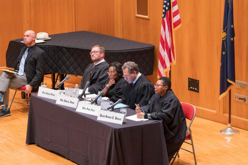 a group of people sitting at a table with microphones
