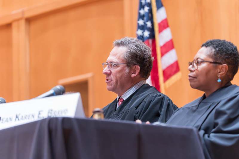 a man in a black robe sitting at a podium