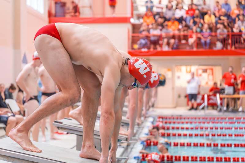 a group of men in swim suits ready to dive into a pool