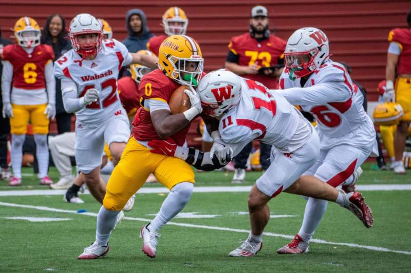 a football player in a red uniform running with a football in the back