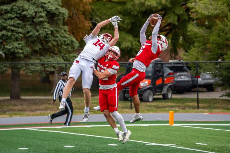 a group of football players jumping for the ball