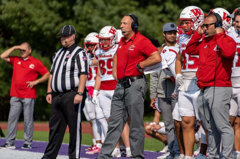 a football coach standing on a field with other football players