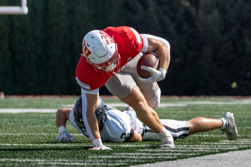 a football player falling down while another player dives