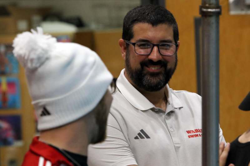 a man in a white shirt and glasses talking to another man