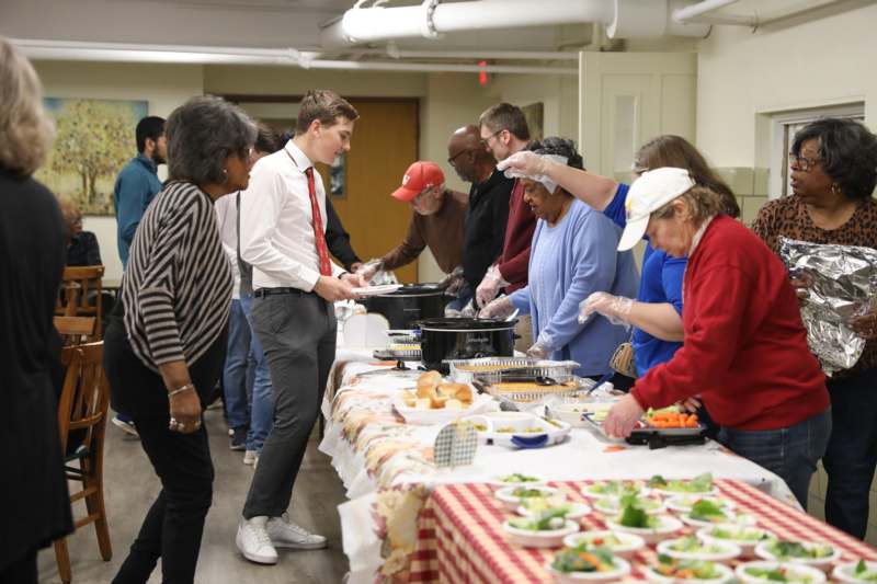 a group of people standing around a table full of food