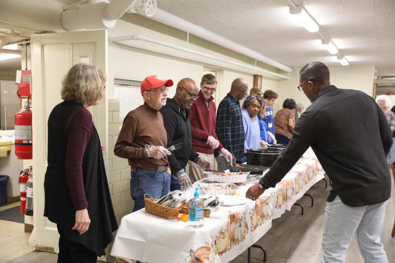 a group of people standing in a line at a buffet