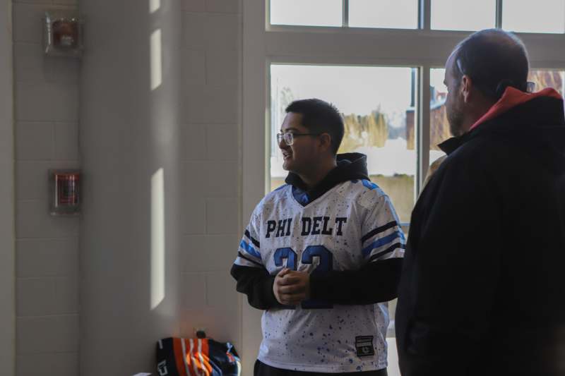 a man in a jersey and glasses standing next to a man in a room