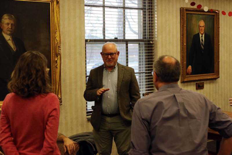 a man in a suit standing in a room with people in front of them